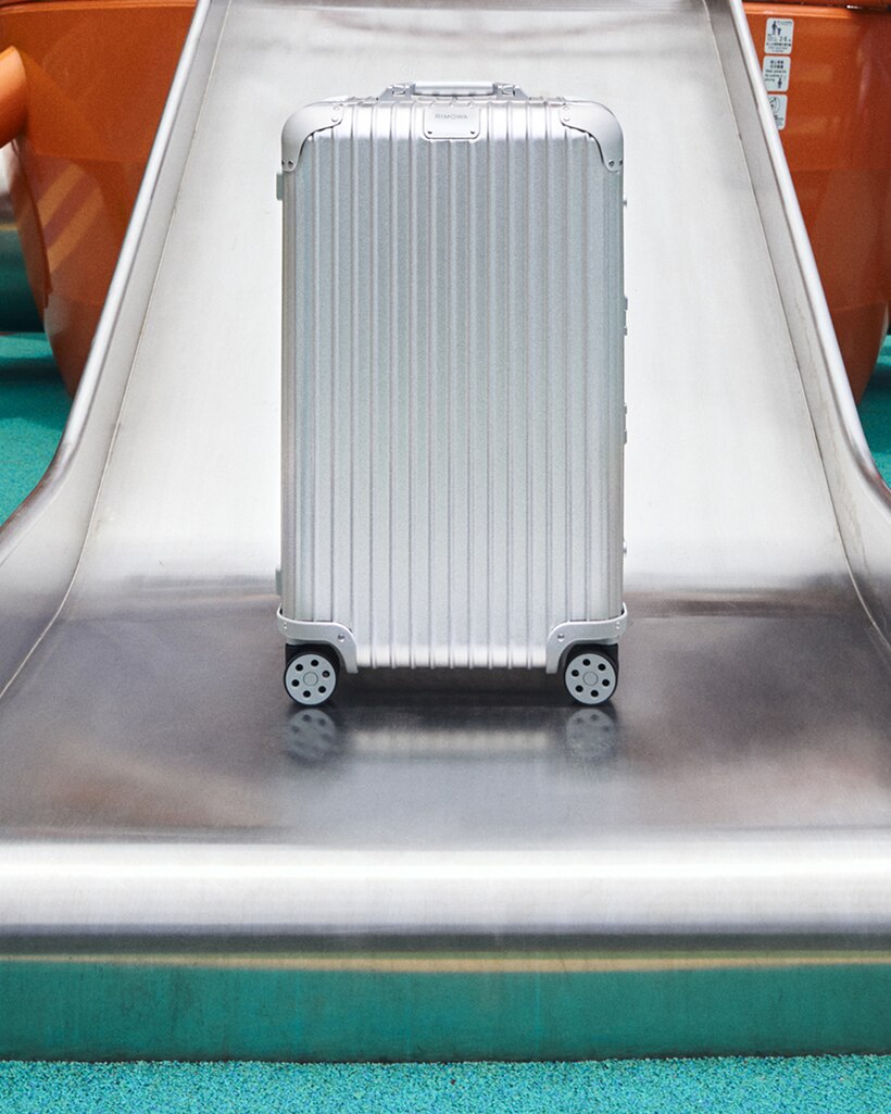 Silver RIMOWA suitcase placed on a metallic slide.